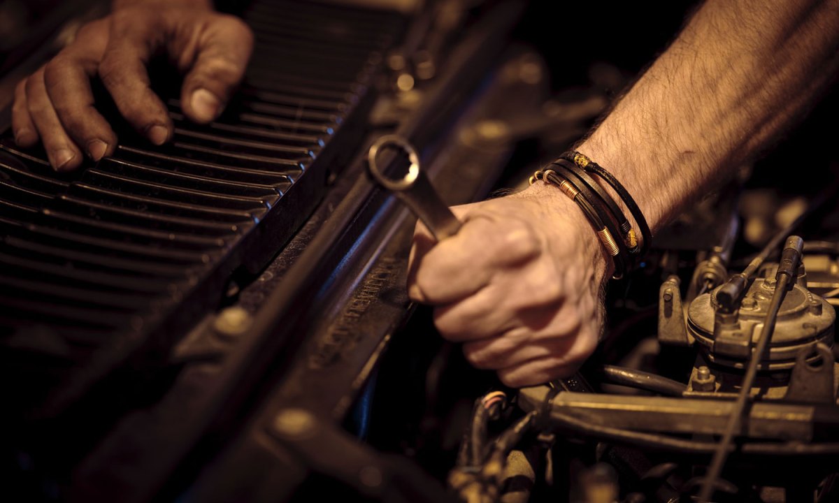 Man working under the hood on a vehicle engine.