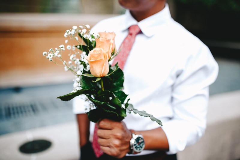 A man presents roses while wearing a great watch.