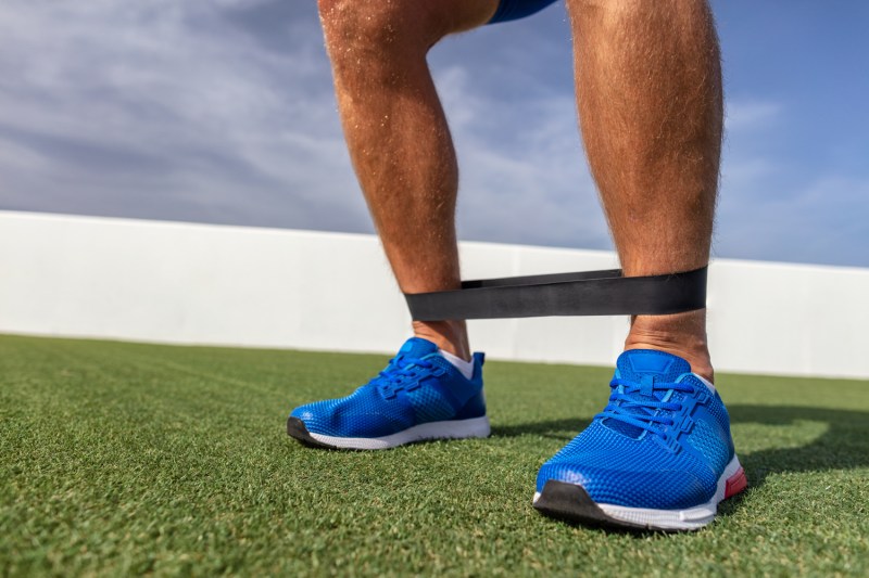 A resistance band around a man's ankles.