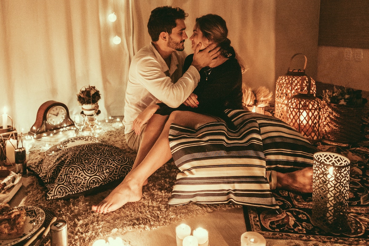 Valentine's Day romantic couple in bed with candles.