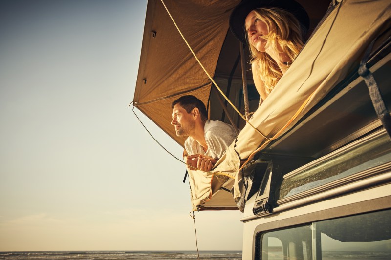 A couple relaxing inside a rooftop tent.