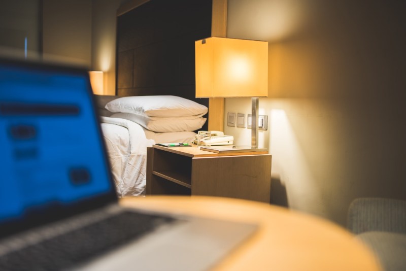 Hotel Room with a Notebook Computer on the Table Near the Bed