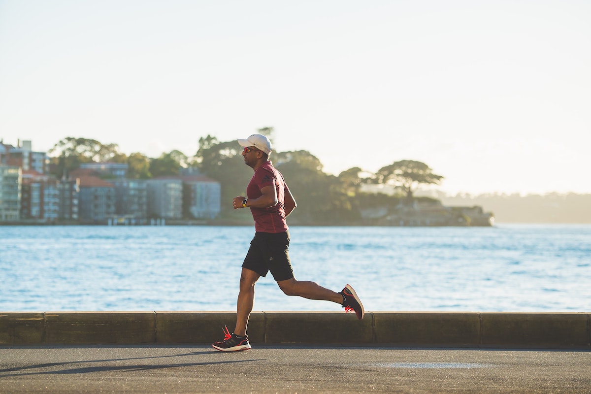 Man running on street by a body of water.