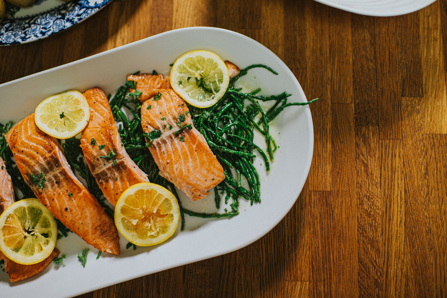 Salmon with vegetables and lemons on an oval plate.