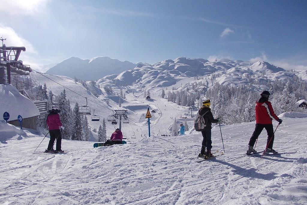 Skiers and snowboards at the edge of slope.