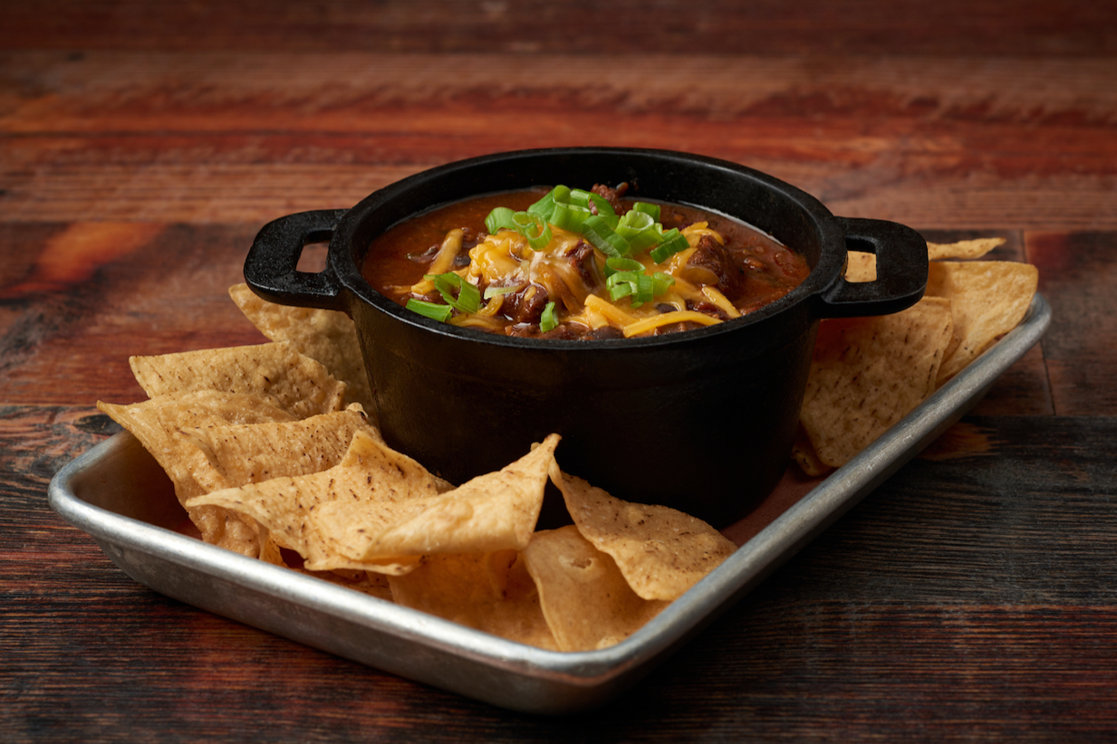 Virgil's chili in a black bowl surrounded by tortilla chips.