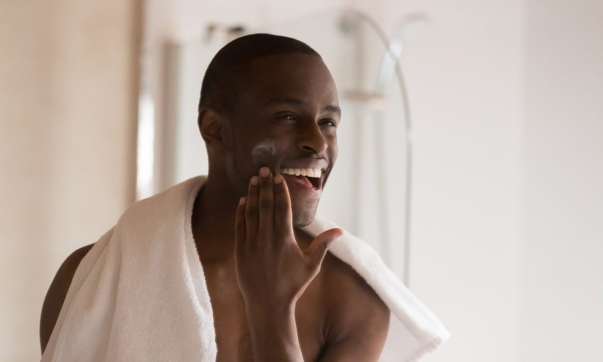 Man putting on face moisturizer.
