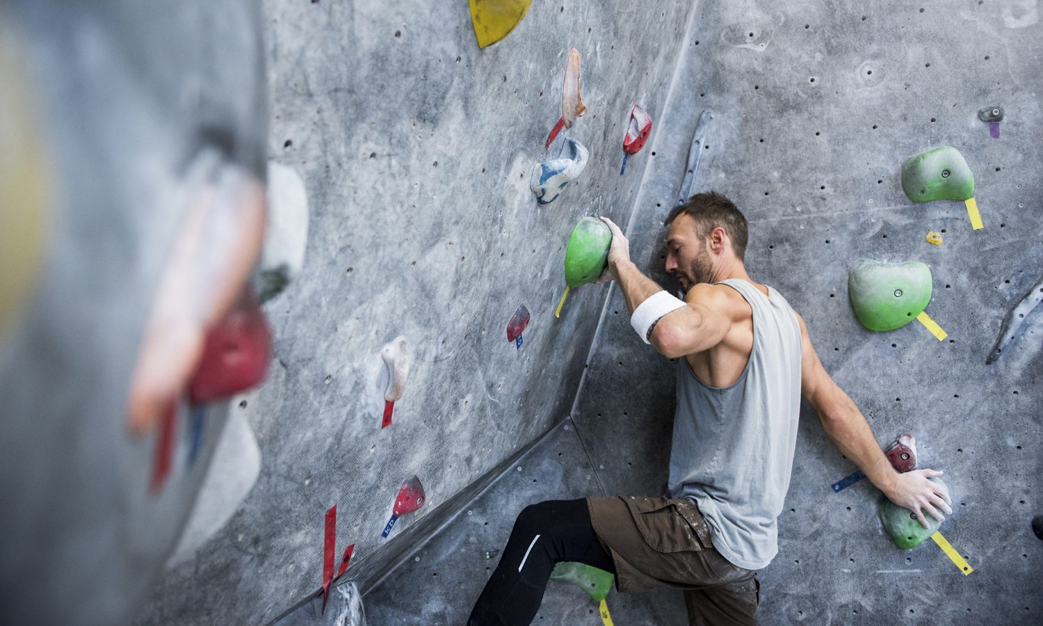 An athletic man climbing on an artificial rock wall.