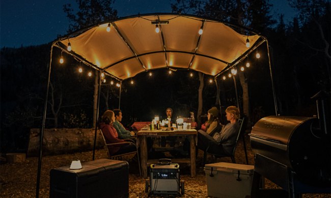 Group of people camping and dining off-grid with solar power.