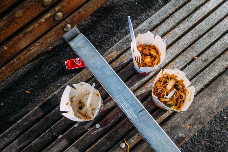 Chinese food leftovers on a wooden bench.