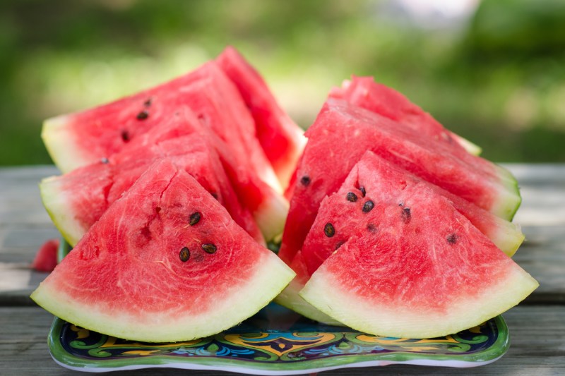 A close-up of watermelon slices served on a tray on a wooden table.