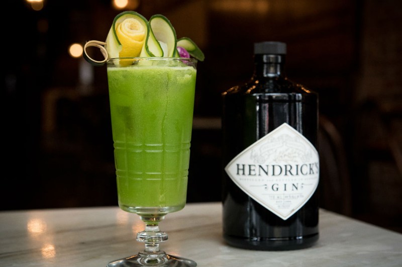 A refreshing glass of Fresh Perspective garnished with vegetables beside a bottle of Hendrick's Gin.
