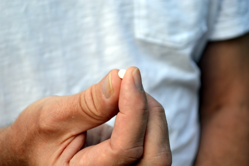Man holding a small white pill