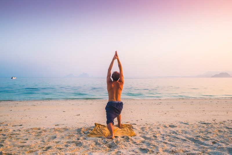 Man practicing yoga on the beach.