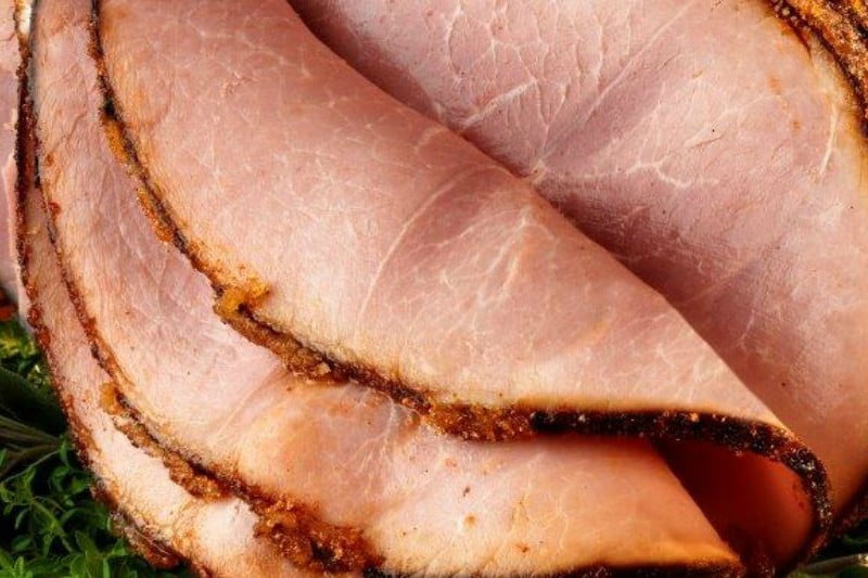 A close-up photo of Logan Farms Honey Glazed Ham, which is partially sliced.