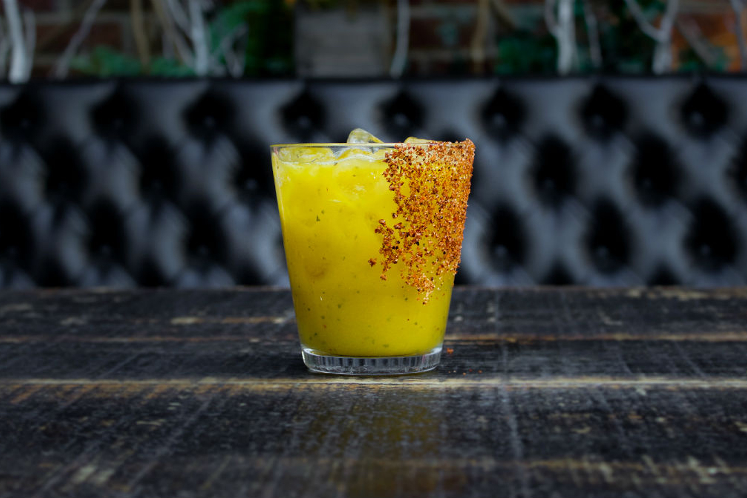 An ice-cold glass of Mango Basil Margarita on black table.