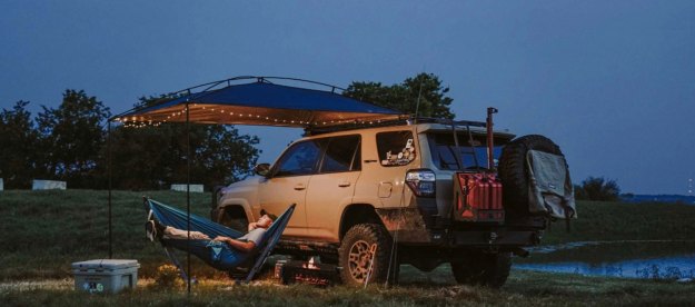 Man relaxing alone under a MoonShade Portable Vehicle Awning while overlanding.