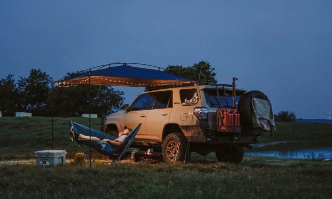 Man relaxing alone under a MoonShade Portable Vehicle Awning while overlanding.
