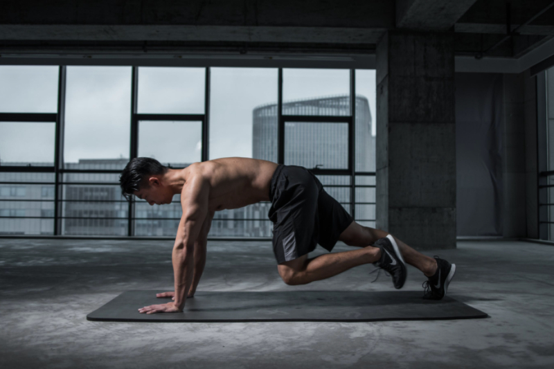 Guy working out is performing a mountain climber on the ground.