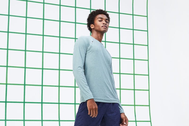 A man in blue long-sleeved shirt posing against a white backdrop with green grids.