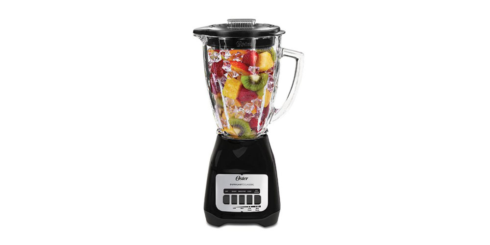 Oster Classic Series 5-Speed Blender filled with fruit on a white background.