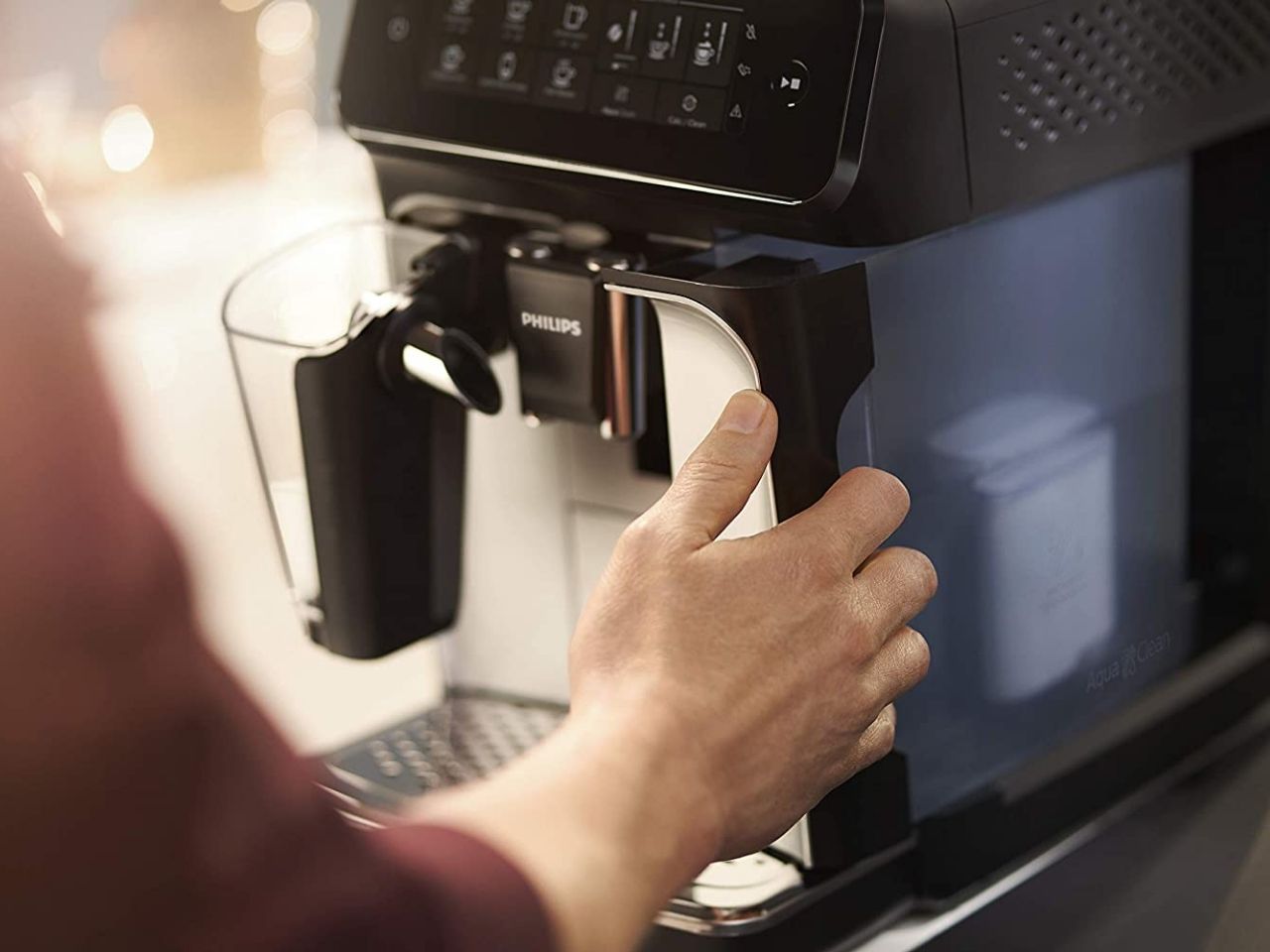 A person touches the front of the Philips 3200 EP3241 espresso machine.