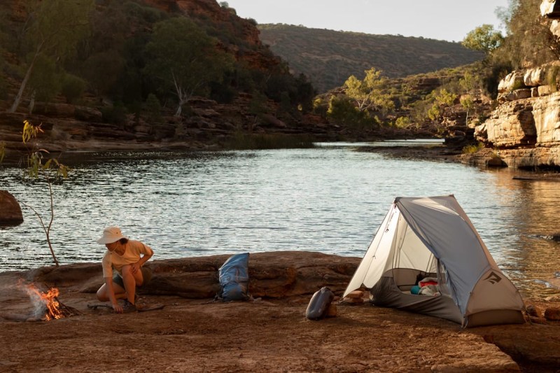 Person camping on a river using a one person tent.