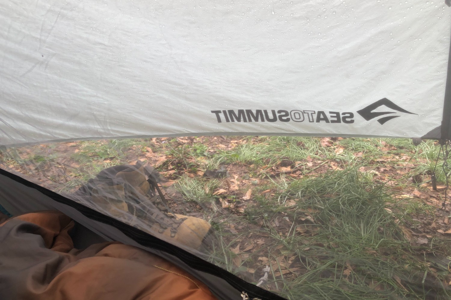 Vestibule view of a one-person tent in the rain.