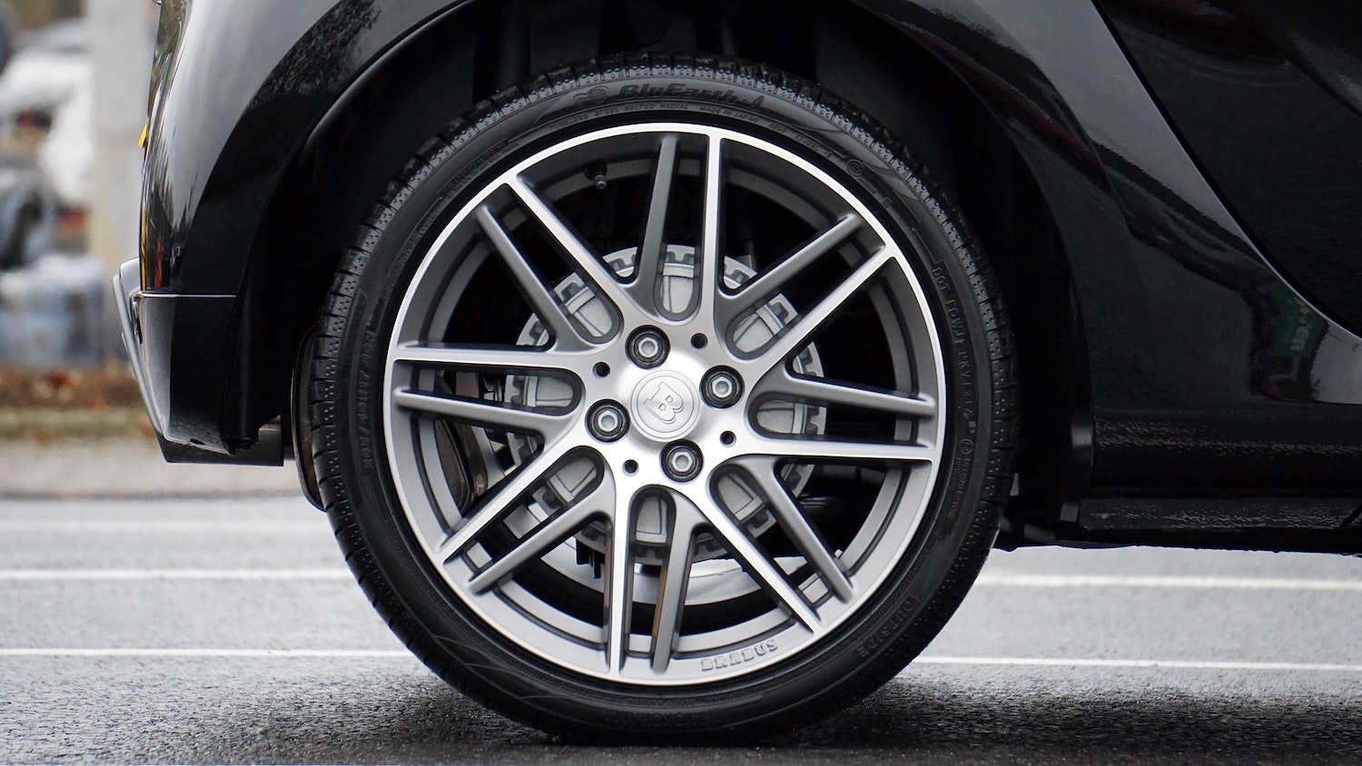 Close up of shiny car tire with Brabus wheels on pavement.