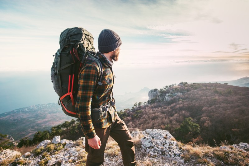 A hiker standing atop a mountain and looking out over the landscape