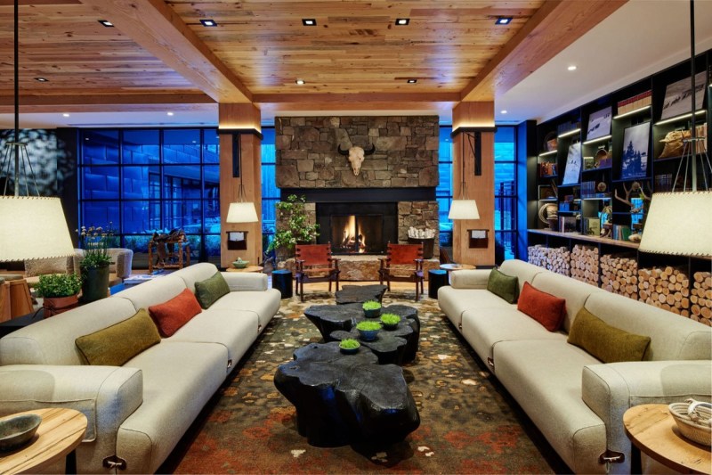 The Cloudveil lobby with sprawling couches, reclaimed wood ceilings, and granite shelving all surrounding a massive fieldstone fireplace, topped with a typical Western cow skull