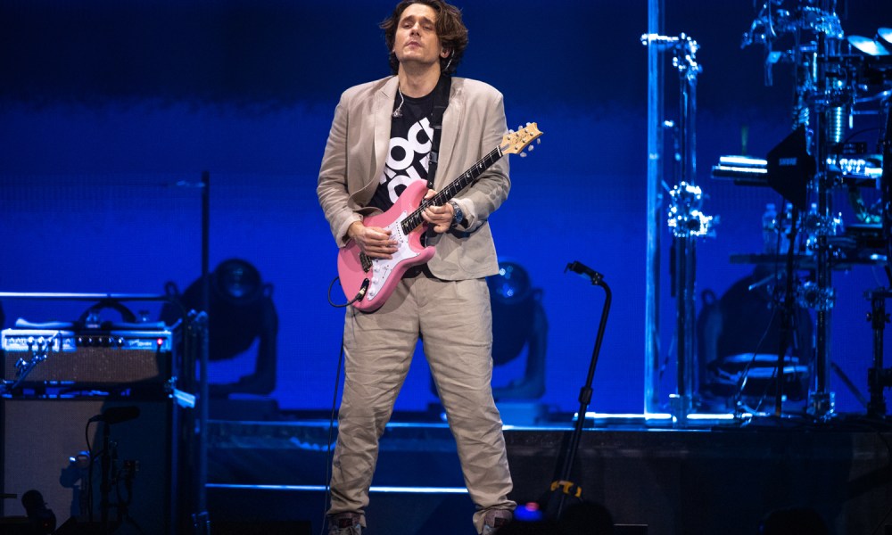 John Mayer strumming his guitar as he performs onstage at The Forum.