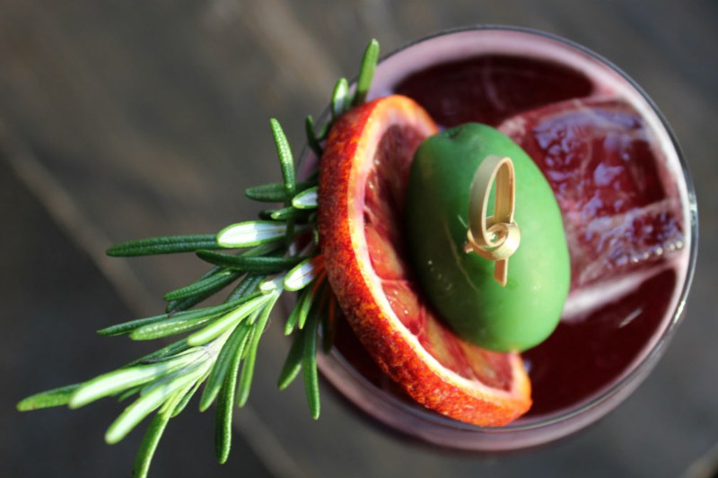 An overhead shot of Winter Spritz garnished with blood orange wheel, green olive, and rosemary sprig.