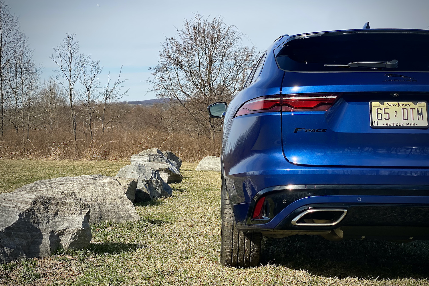 Side view of 2022 Jaguar F-Pace R Dynamic S rear end with rocks in the background.