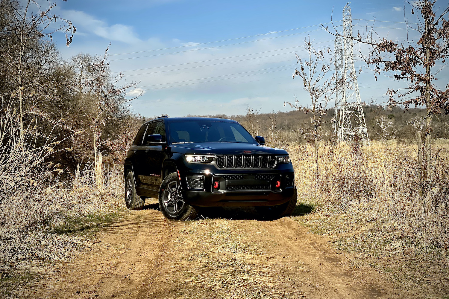 Front side angle of 2022 Jeep Grand Cherokee Trailhawk from passenger's side on a dirt trail.