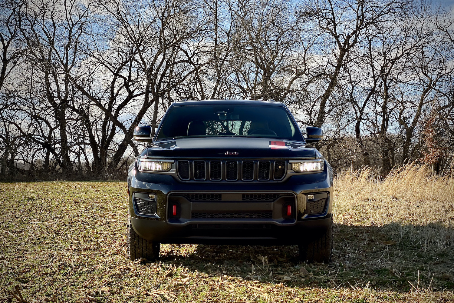 Front view of 2022 Jeep Grand Cherokee Trailhawk with trees in the background.