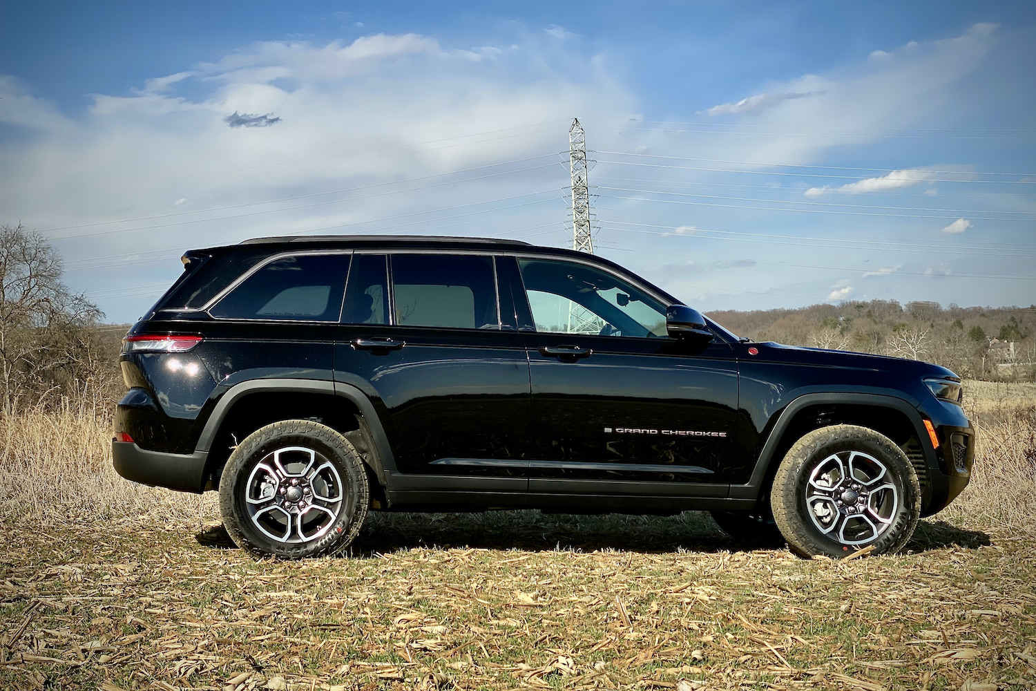 Side profile of 2022 Jeep Grand Cherokee Trailhawk in a grassy field.