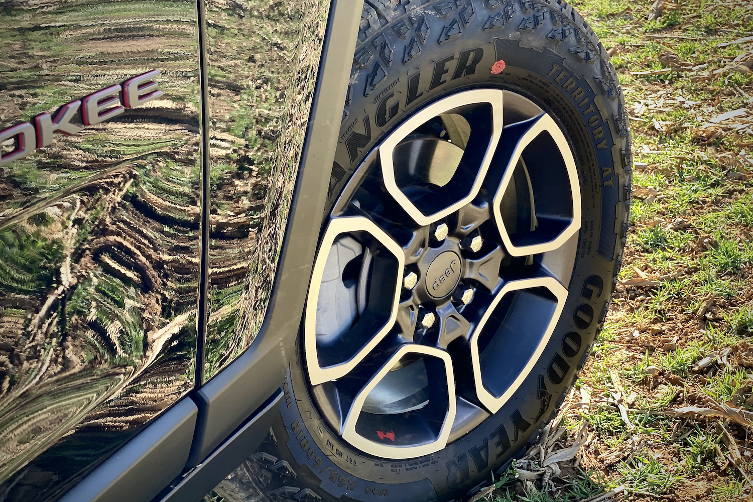 2022 Jeep Grand Cherokee Trailhawk front wheel in a grassy field.