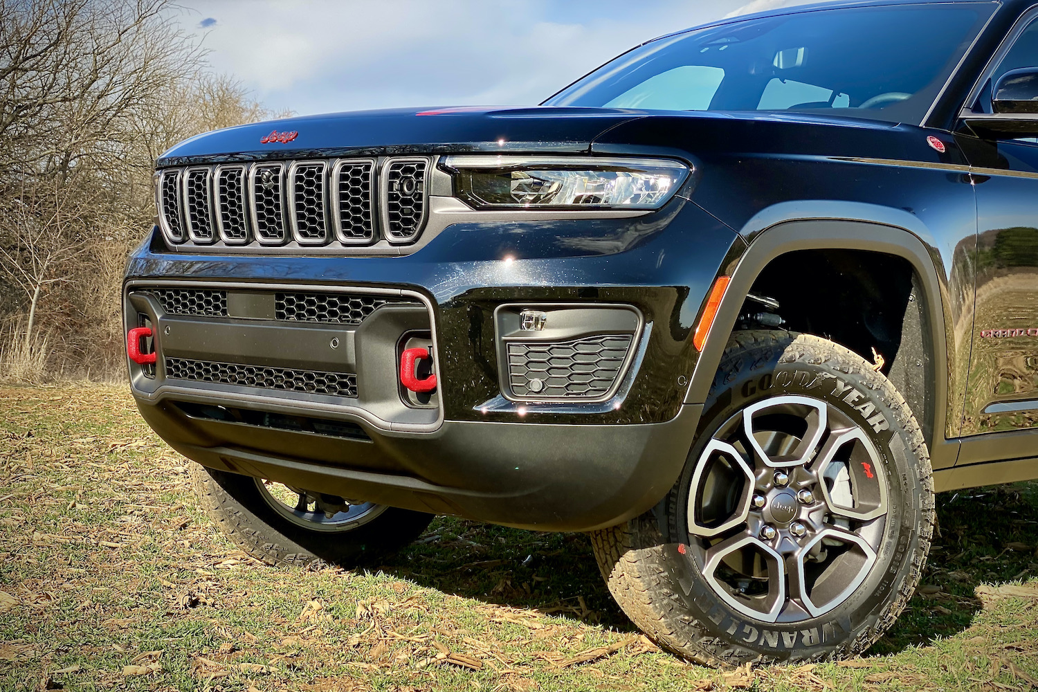 Front end of 2022 Jeep Grand Cherokee Trailhawk from driver's side with trees in the background.