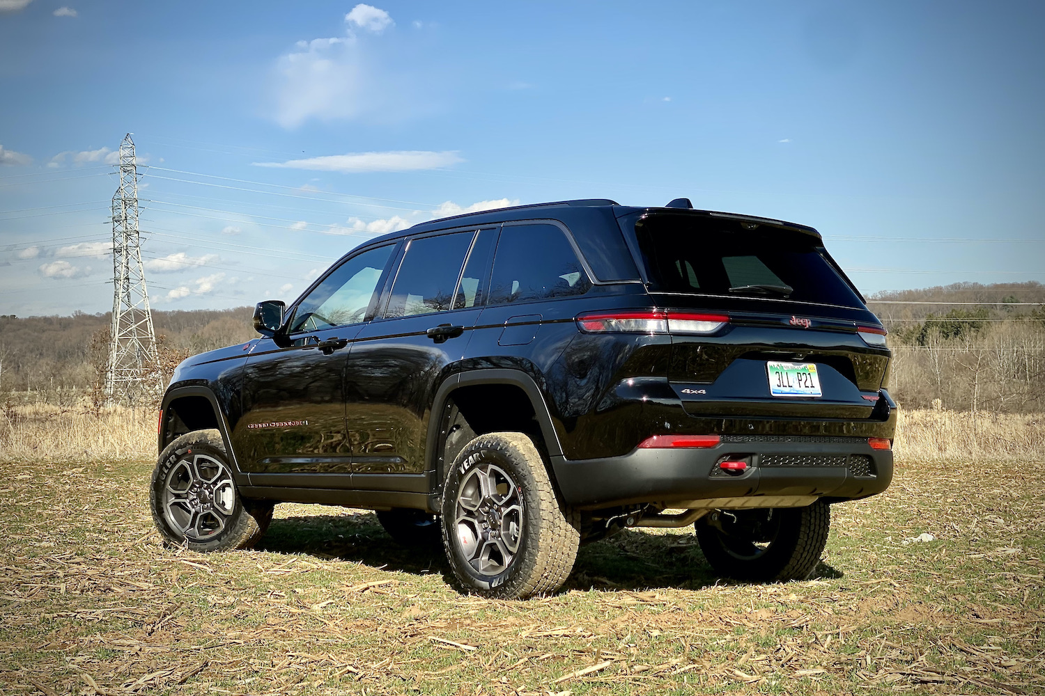 Rear end of 2022 Jeep Grand Cherokee Trailhawk from passenger's side angle in front of bushes.