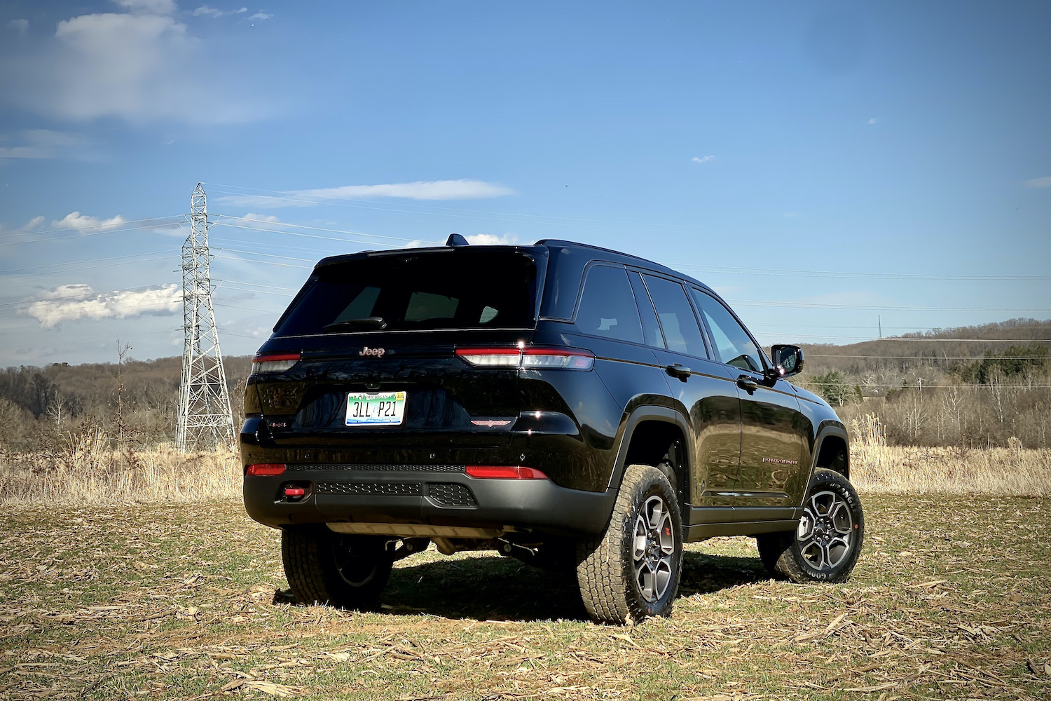 Rear end of 2022 Jeep Grand Cherokee Trailhawk from passenger's side on a grassy field.