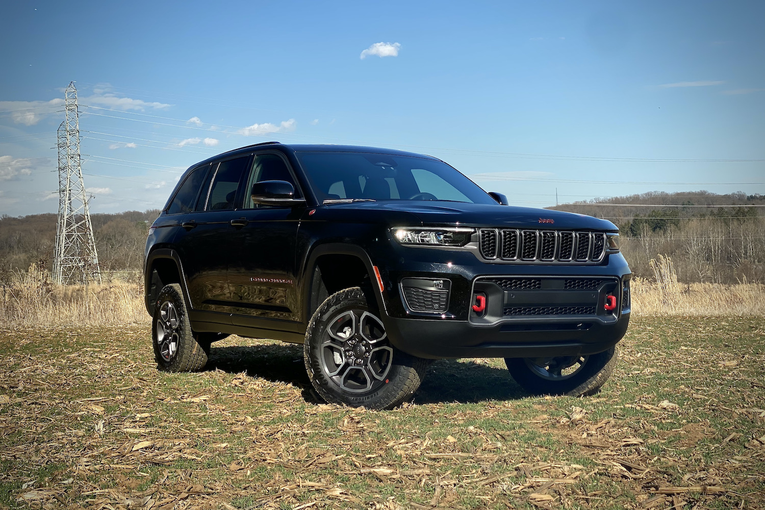 2022 Jeep Grand Cherokee Trailhawk front end from passenger's side with bushes in the back.