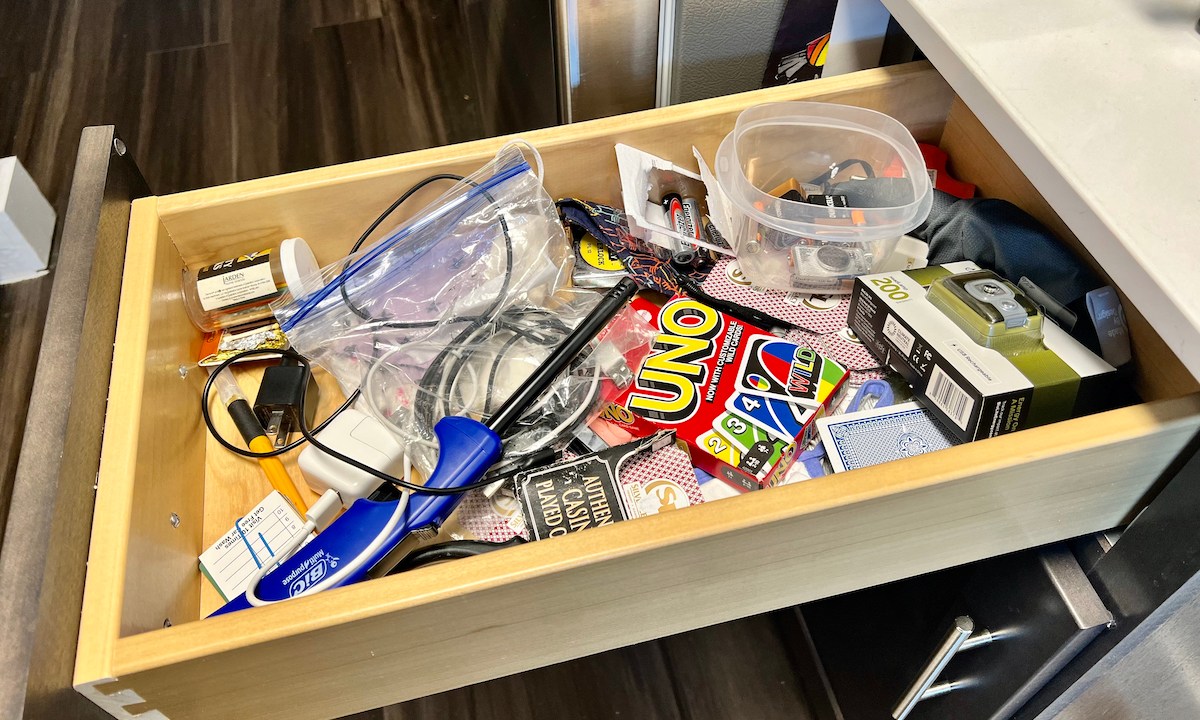 An open kitchen junk drawer filled with assorted home items.