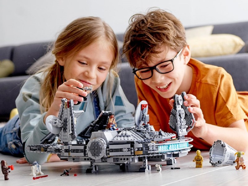 Two kids playing with the Lego Millennium Falcon.
