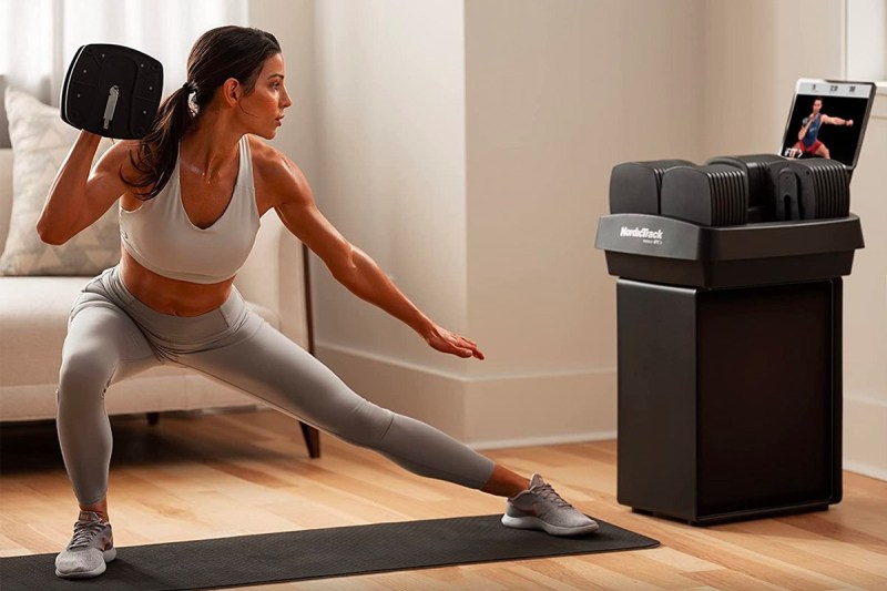 A woman works out with the NordicTrack iSelect adjustable dumbbells.