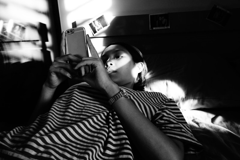 A woman uses her smartphone while lying in bed