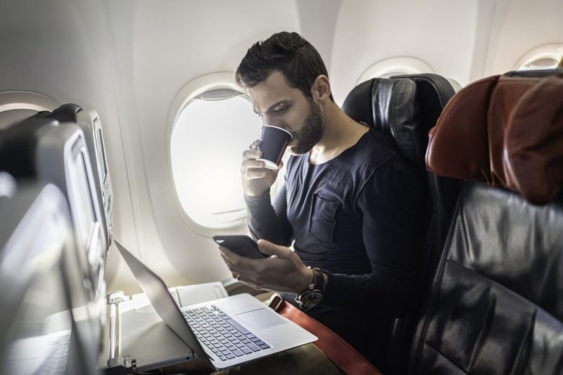 A person on a plane on their laptop and phone