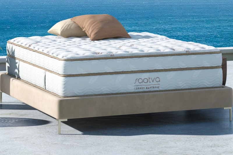 A Saatva Classic mattress lies on a patio facing the ocean.