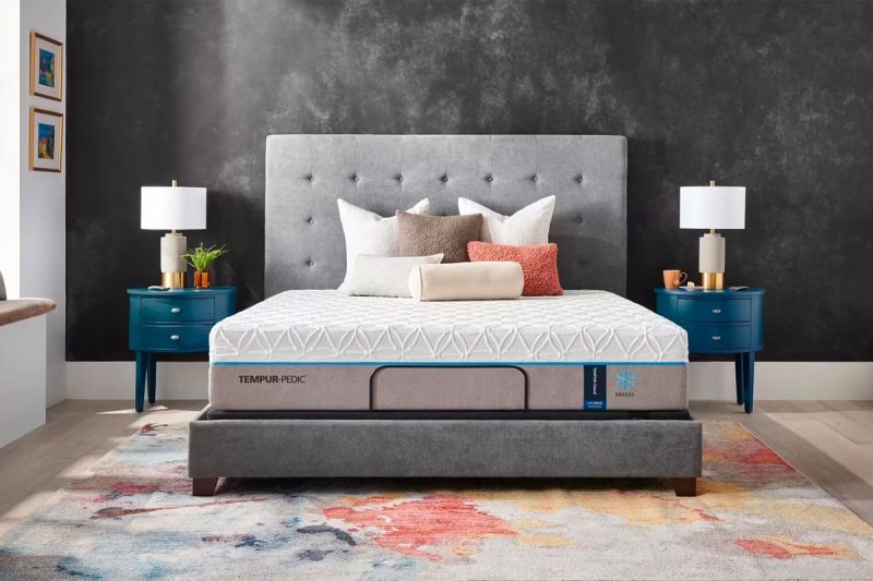 Tempur-Pedic’s Breeze 2.0 mattress is place on a bed frame and covered with pillows in a bedroom.