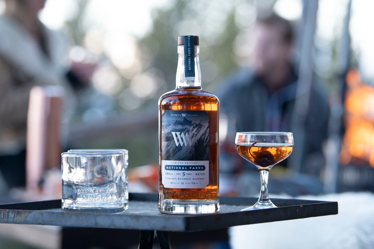 A bottle of Wyoming Whiskey National Parks Limited Edition whiskey on a table with cocktail glasses.